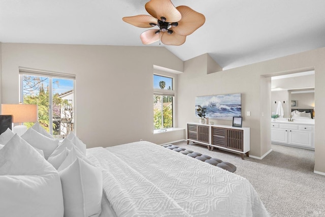 carpeted bedroom with ensuite bath, lofted ceiling, baseboards, and ceiling fan