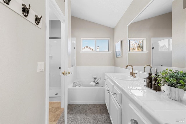 bathroom featuring a shower stall, vanity, a garden tub, and vaulted ceiling