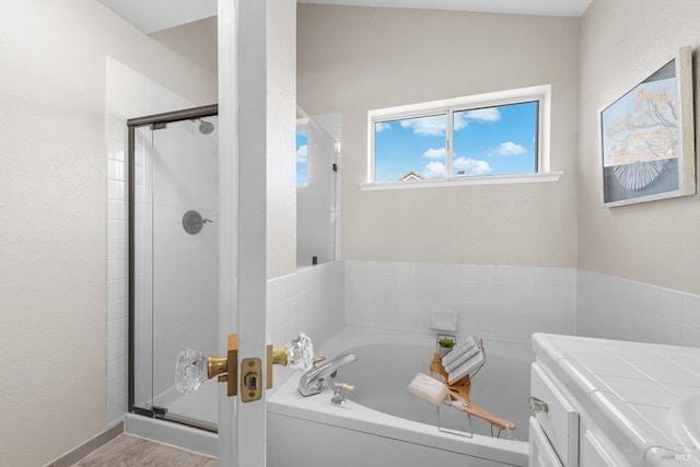 bathroom featuring a stall shower, vanity, and a garden tub