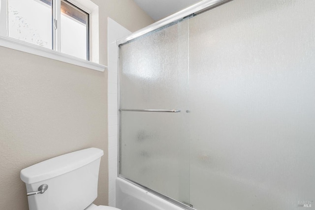 full bath featuring toilet and combined bath / shower with glass door