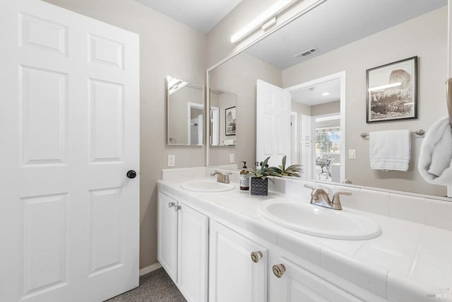 full bath featuring double vanity, visible vents, and a sink