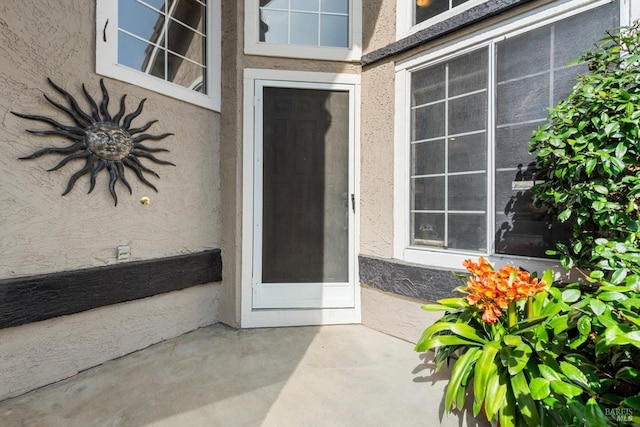 entrance to property featuring a patio and stucco siding