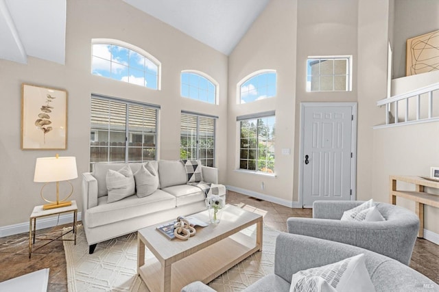 living room with visible vents, baseboards, and high vaulted ceiling