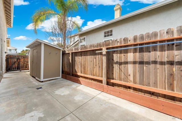 view of patio with a storage unit, a fenced backyard, and an outdoor structure