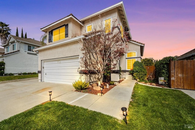 view of front facade with a front lawn, fence, concrete driveway, stucco siding, and an attached garage