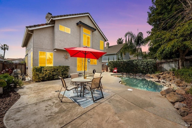 back of house with a fenced in pool, stucco siding, a chimney, a fenced backyard, and a patio