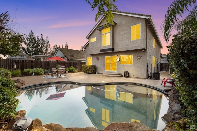 pool at dusk featuring a fenced backyard, a fenced in pool, and a patio