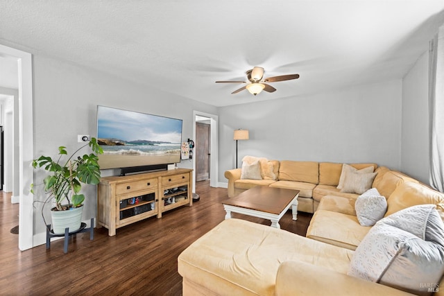 living area featuring baseboards, dark wood finished floors, and a ceiling fan