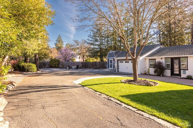 view of front of home featuring a front lawn, fence, aphalt driveway, roof with shingles, and an attached garage