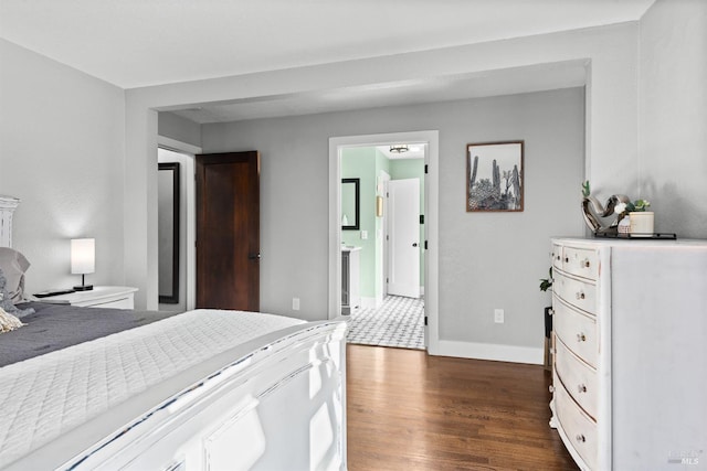 bedroom featuring dark wood-style floors, baseboards, and connected bathroom