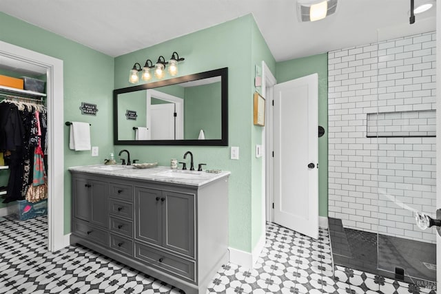 bathroom with visible vents, a sink, double vanity, tiled shower, and a spacious closet