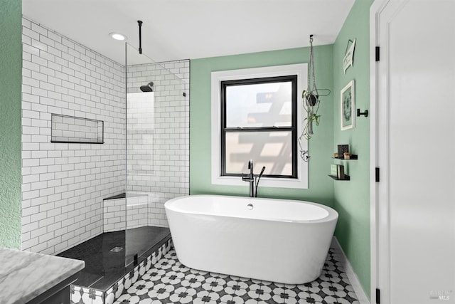 bathroom with baseboards, a freestanding bath, a tile shower, recessed lighting, and vanity