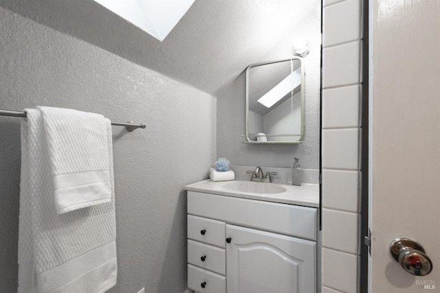 bathroom with a skylight, vanity, and a textured wall