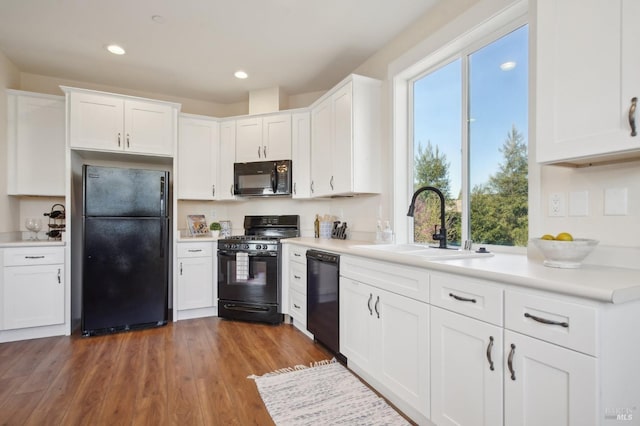 kitchen featuring white cabinetry, black appliances, and a sink