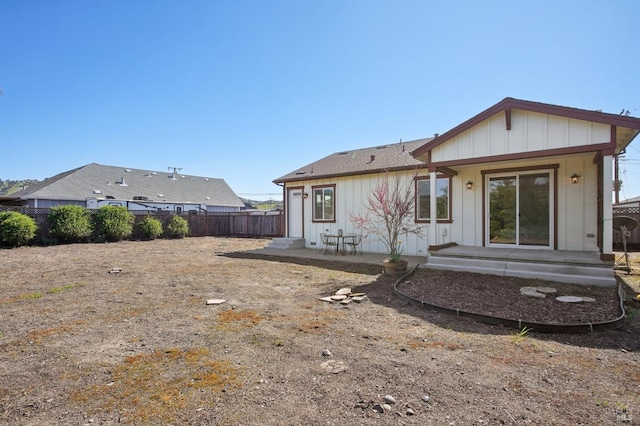 rear view of property with board and batten siding and fence