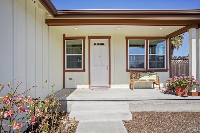 doorway to property with covered porch and fence