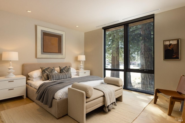 bedroom featuring light wood finished floors, recessed lighting, floor to ceiling windows, and multiple windows