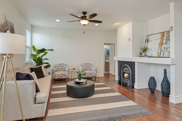 living area featuring a fireplace with flush hearth, recessed lighting, baseboards, and wood finished floors