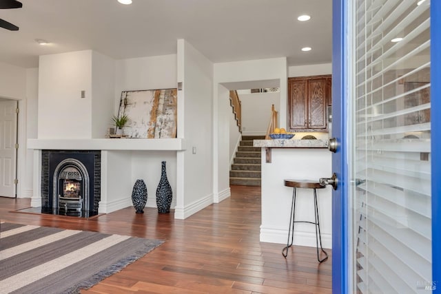 living room with wood finished floors, baseboards, recessed lighting, a fireplace, and stairs