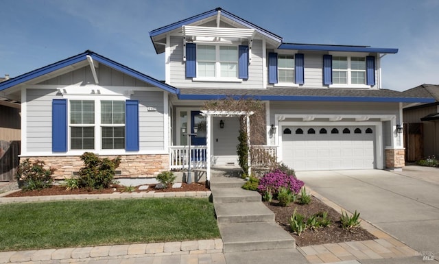 craftsman house with stone siding, an attached garage, board and batten siding, and driveway