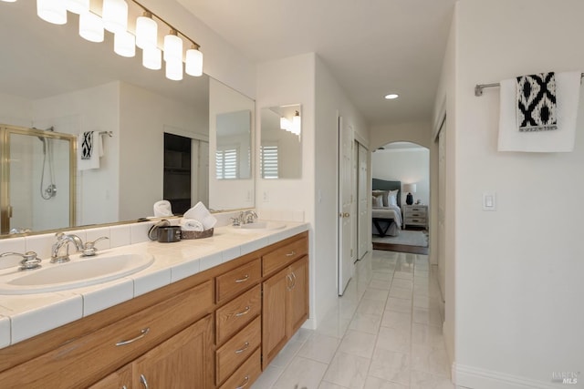 ensuite bathroom with double vanity, a stall shower, ensuite bath, and a sink