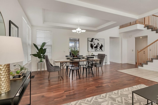 dining area with a notable chandelier, stairway, a raised ceiling, and wood finished floors