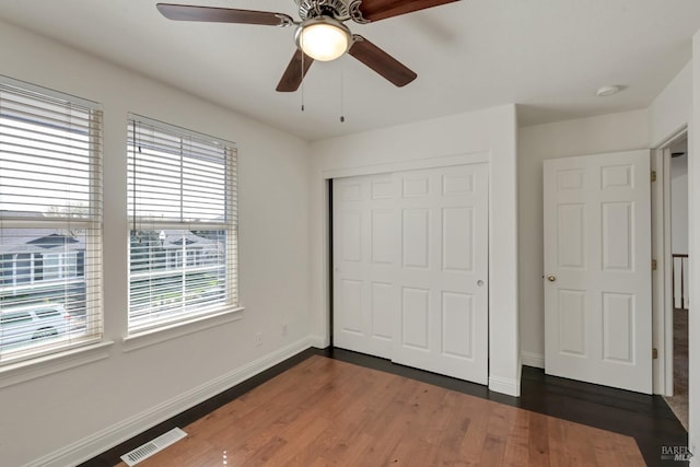 unfurnished bedroom featuring visible vents, baseboards, a closet, and wood finished floors