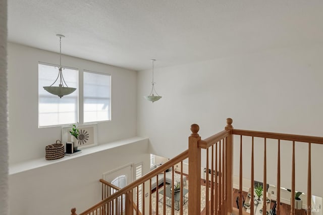 corridor featuring an upstairs landing and a textured ceiling