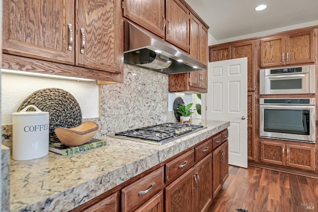 kitchen featuring tasteful backsplash, dark wood finished floors, ventilation hood, appliances with stainless steel finishes, and light countertops