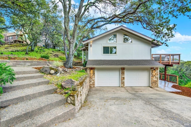 exterior space featuring concrete driveway, an attached garage, stone siding, and roof with shingles