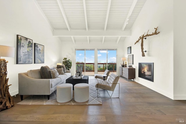 living area with beam ceiling, a glass covered fireplace, baseboards, and wood finished floors