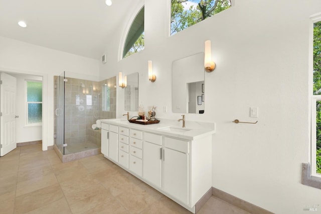 full bathroom featuring a shower stall, double vanity, a sink, and baseboards