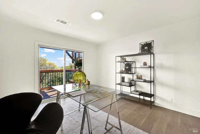 home office with wood finished floors, visible vents, and baseboards