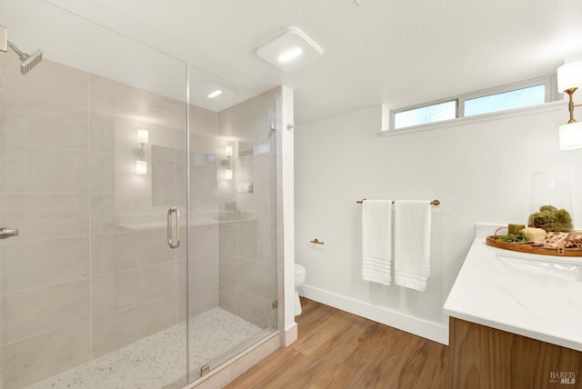 full bath featuring a shower stall, baseboards, toilet, wood finished floors, and vanity