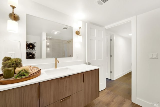 full bathroom with vanity, wood finished floors, visible vents, and a stall shower