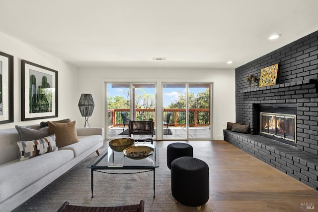 living room featuring wood finished floors, a fireplace, visible vents, and recessed lighting