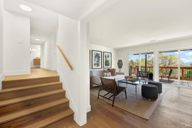 living room with stairway, wood finished floors, and baseboards