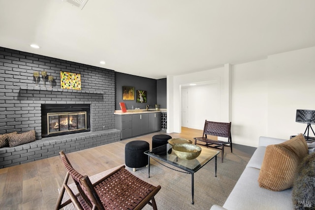 living room with visible vents, recessed lighting, a fireplace, bar area, and light wood-type flooring