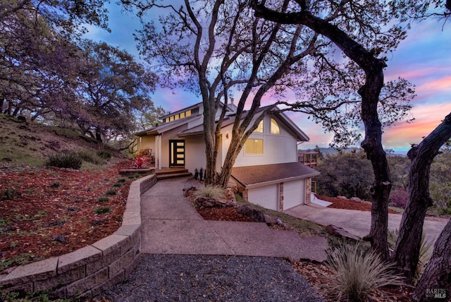 mid-century modern home featuring driveway, a garage, and stucco siding
