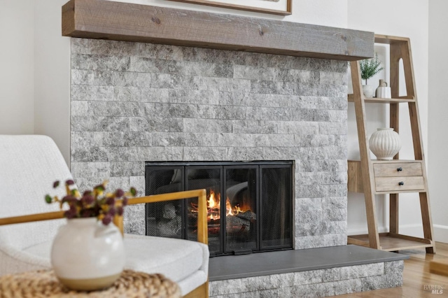 room details with a glass covered fireplace, wood finished floors, and baseboards