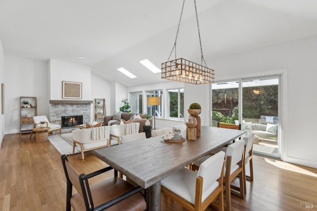 dining space with a stone fireplace, lofted ceiling, and wood finished floors