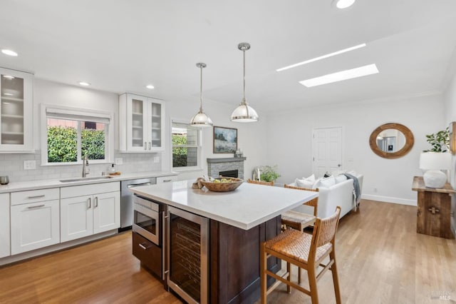 kitchen with beverage cooler, a breakfast bar, light countertops, appliances with stainless steel finishes, and a sink