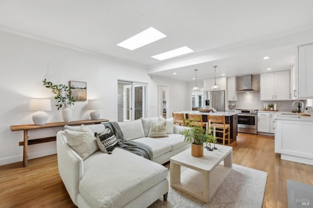 living area with crown molding, a skylight, recessed lighting, and light wood-type flooring