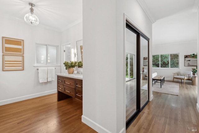 hallway featuring crown molding, a notable chandelier, wood finished floors, and baseboards