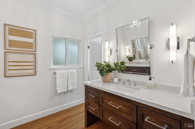 bathroom with baseboards, wood finished floors, ornamental molding, and vanity