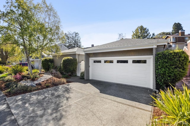 ranch-style home featuring a garage and roof with shingles