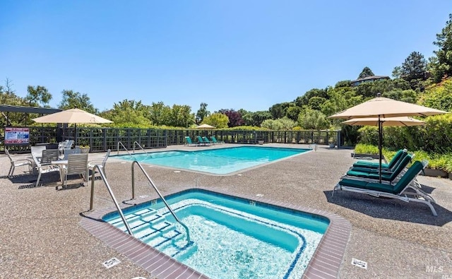 community pool with a patio area, a community hot tub, and fence