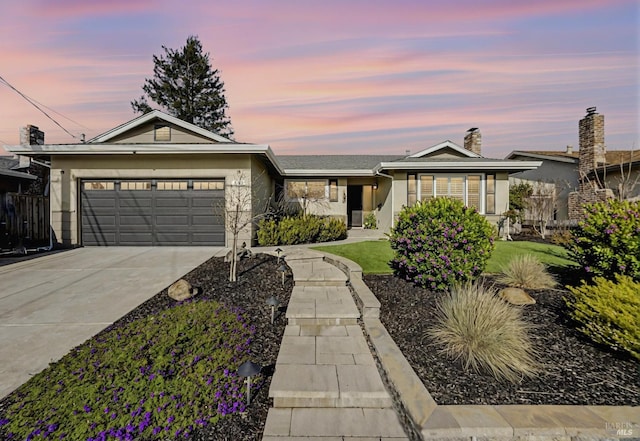 ranch-style home with fence, concrete driveway, a chimney, a yard, and a garage