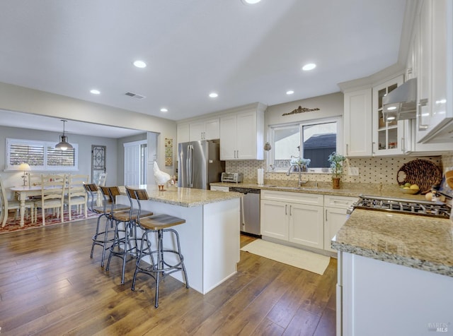 kitchen with visible vents, a sink, under cabinet range hood, appliances with stainless steel finishes, and white cabinetry