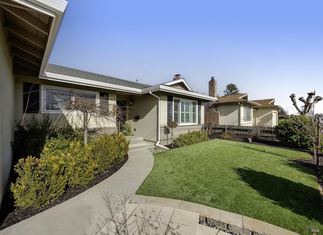 single story home with stucco siding, a chimney, a front yard, and fence